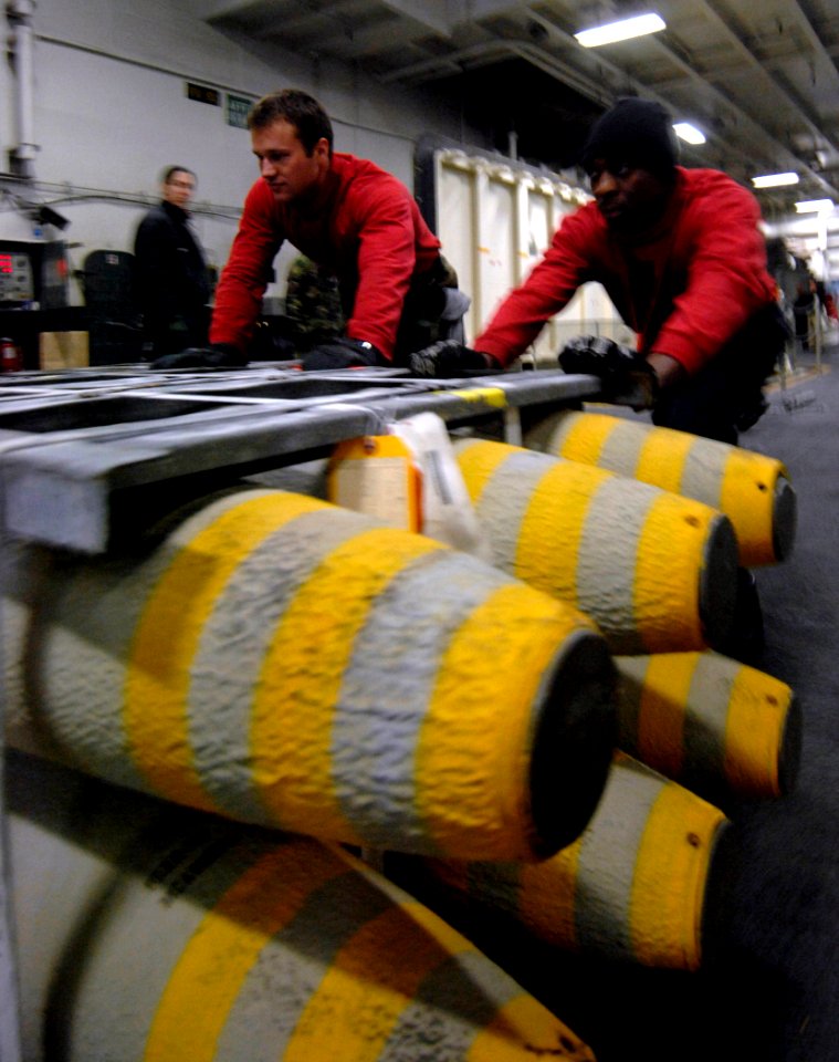 US Navy 070208-N-5345W-010 Aviation Ordnanceman Airman Scott Davis, left, and Aviation Ordnanceman Airman Apprentice Willie Brigman push a pallet of BLU-110 general purpose bombs into position before they are lowered to a weapo