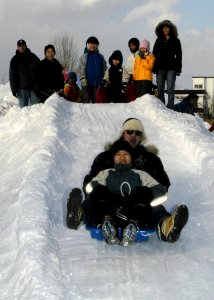 US Navy 070208-N-4649C-125 Ship's Serviceman 2nd Class Harlig Medina slides down a snow slide as others look on at the Kosho Gakuen Home for Children in Sapporo, Japan