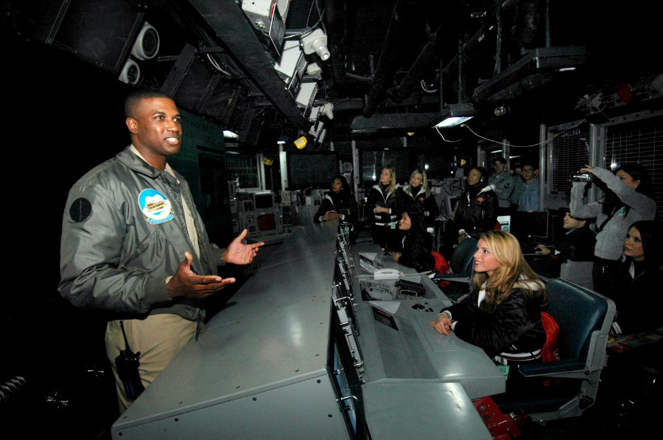 US Navy 070209-N-7883G-011 Lt. Arnold Roper, from Philadelphia, briefs the Tampa Bay Buccaneers Cheerleaders on the daily routine inside USS Kitty Hawk (CV 63) Combat Direction Center (CDC)