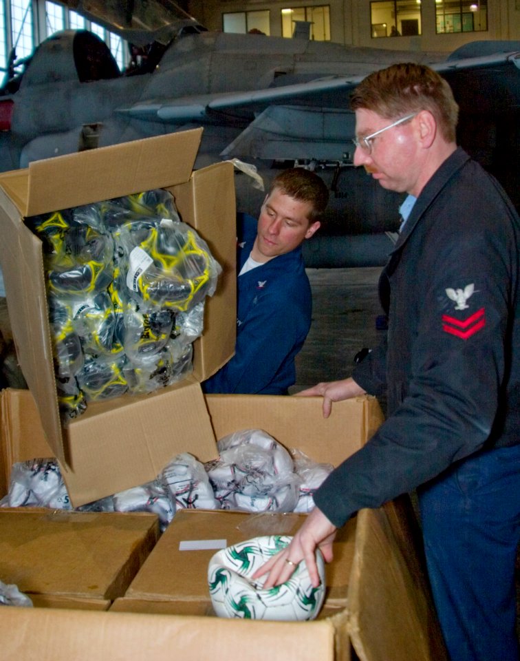 US Navy 070214-N-9150R-001 Sailors attached to the Scorpions of Electronic Attack Squadron One Three Two (VAQ-132) based at Naval Air Station Whidbey Island load donated soccer balls into a container for shipment