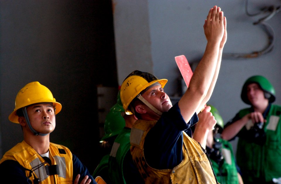 US Navy 070214-N-9712C-002 Boatswain's Mate 3rd Class Ronnie Davis signals how far the pallet is from the rig aboard the Nimitz-class aircraft carrier USS Ronald Reagan's (CVN 76) replenishment station seven