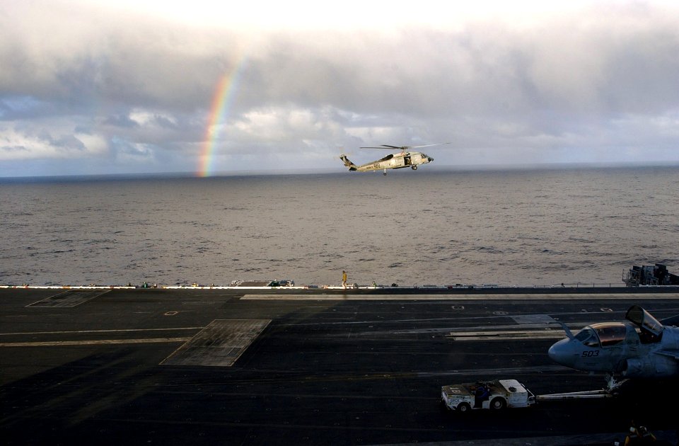 US Navy 070215-N-4009P-294 A rainbow appears in the distance as a SH-60F Seahawk assigned to the Black Knights of Helicopter Anti-Submarine Squadron Four (HS-4) prepares to land on the flight deck of the Nimitz-cl