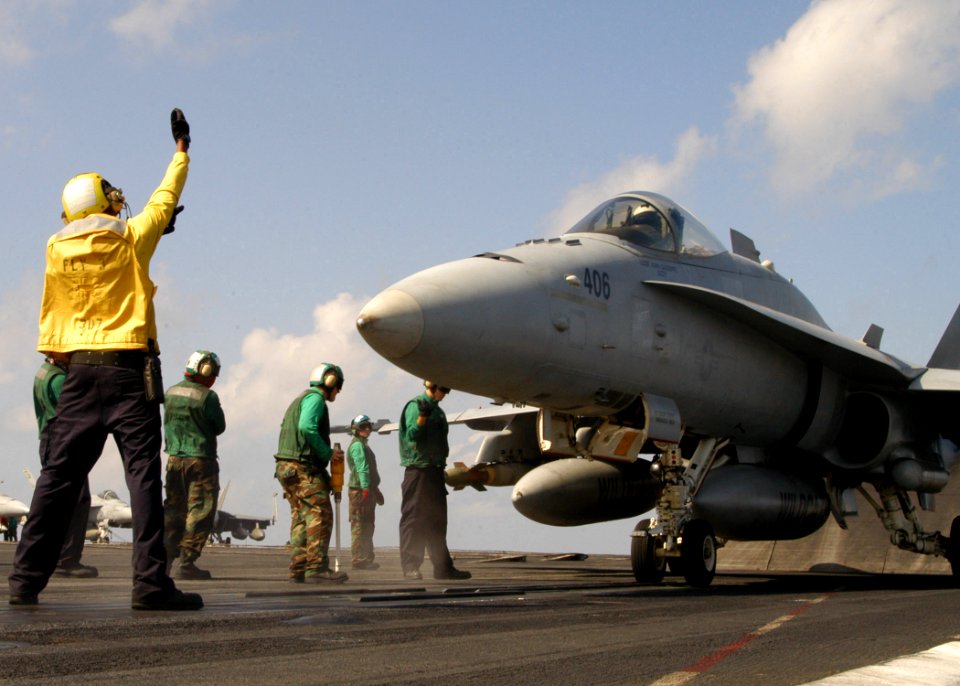 US Navy 070218-N-8446A-001 A plane director moves an F-A-18C Hornet assigned to the Wildcats of Strike Fighter Squadron (VFA-83) into launch position aboard Nimitz-class aircraft carrier USS Dwight D. Eisenhower (