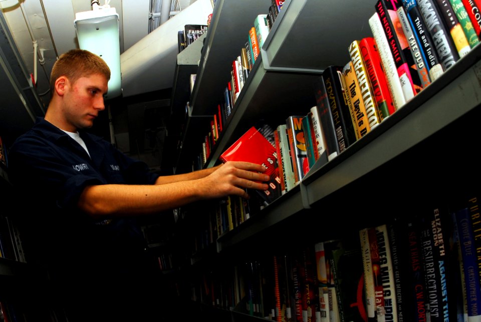 US Navy 070224-N-9928E-020 Airman Rick Mowry places books in back on shelves in the ship's library aboard Nimitz-class aircraft carrier USS John C. Stennis (CVN 74)