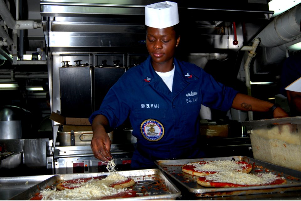 US Navy 070217-N-3038W-135 Operations Specialist 2nd Class Tracey Nkrumah puts toppings on a pizza on the forward mess decks in preparation for lunch and dinner aboard the Nimitz-class aircraft carrier USS John C. Stennis (CVN