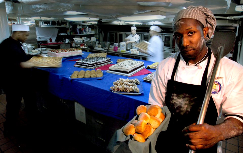 US Navy 070227-N-3729H-092 Culinary Specialist 3rd Class Ugene Ward, head baker aboard USS John C. Stennis (CVN 74), displays a pan of fresh rolls