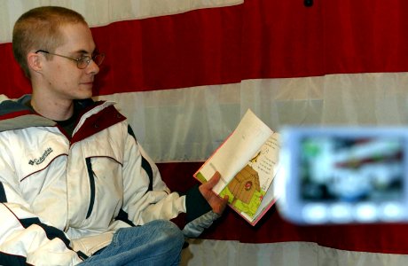 US Navy 070228-N-2143T-002 Electronics Technician 2nd Class Joshua Nyegard, assigned to USS Nevada (SSBN 733), reads a children's book to his kids during a United Through Reading (UTR) taping