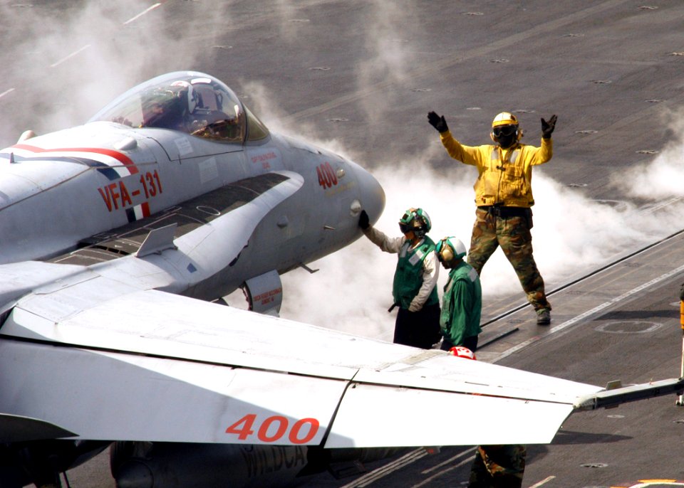 US Navy 070214-N-8446A-010 A plane director signals to the pilot of an F-A-18C Hornet assigned to the Wildcats of Strike Fighter Squadron One Three One (VFA-131) as he positions the aircraft for launch