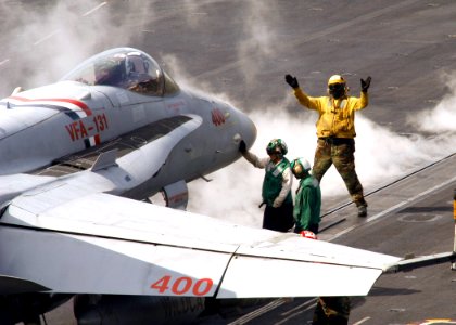 US Navy 070214-N-8446A-010 A plane director signals to the pilot of an F-A-18C Hornet assigned to the Wildcats of Strike Fighter Squadron One Three One (VFA-131) as he positions the aircraft for launch