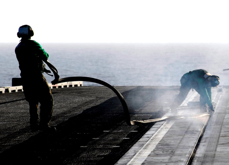 US Navy 070301-N-3729H-031 Sailors assigned to air department's launch and recovery division aboard USS John C. Stennis (CVN 74) uncover the catapult track by removing large rubber strips designed to keep foreign objects out of