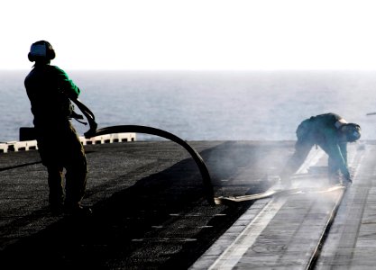 US Navy 070301-N-3729H-031 Sailors assigned to air department's launch and recovery division aboard USS John C. Stennis (CVN 74) uncover the catapult track by removing large rubber strips designed to keep foreign objects out of