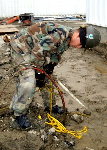 US Navy 070302-N-6247M-017 Construction Electrician Constructionman Joshua Gonzales, from San Diego, Calif., pulls up old wires outside a prefabricated building his unit is working on