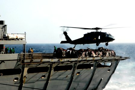 US Navy 070228-N-9928E-186 Sailors assigned to Military Sealift Command (MSC) fast combat support ship USNS Arctic (T-AOE 8) load supplies onto a cargo hook underneath an MH-60S Seahawk
