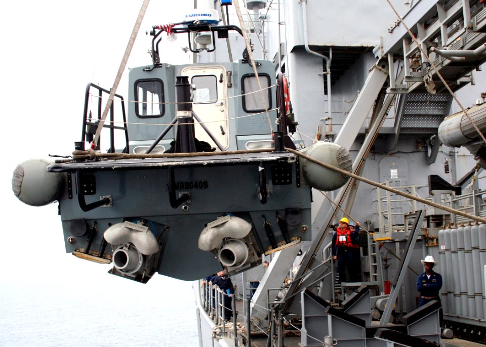 US Navy 070220-N-6710M-003 Sailors on board dock landing ship USS Tortuga (LSD 46) work together to recover a small boat from the ship's port side