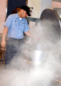 US Navy 070221-N-6247M-026 Culinary Specialist Seaman Danny Viera, from Florida, Puerto Rico, washes out a large kettle steamer in the Admiral Nimitz Dining Facility located on Naval Air Station Whidbey Island photo