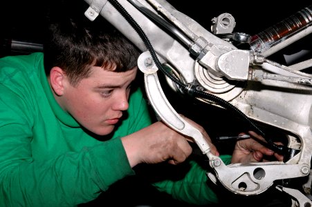 US Navy 070224-N-9760Z-027 Aviation Electrician's Mate Airman Brian Mollitor assigned to the Sunliners of Strike Fighter Squadron (VFA) 81 works on the wheel safety wiring of an F-A-18 Hornet aboard nuclear