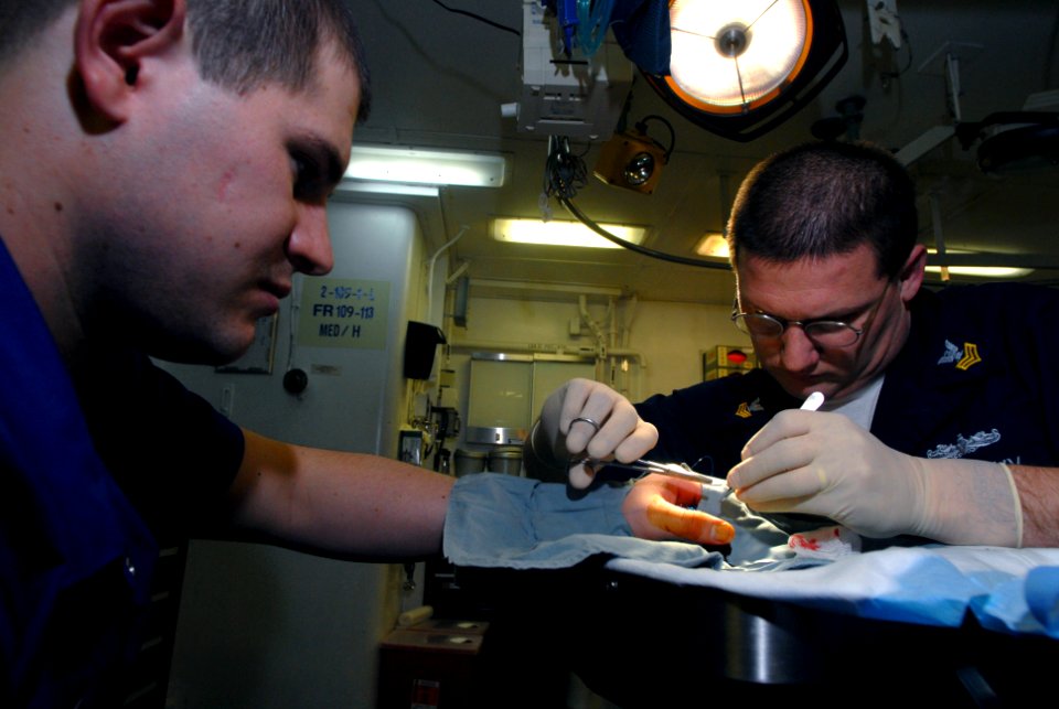 US Navy 070302-N-2659P-127 Hospital Corpsman 1st Class Benjamin Morgan stitches a laceration on the hand of Aviation Boatswain's Mate Airman Apprentice Janssen Eilenberger in the medical ward aboard USS John C. Stennis (CVN 74)