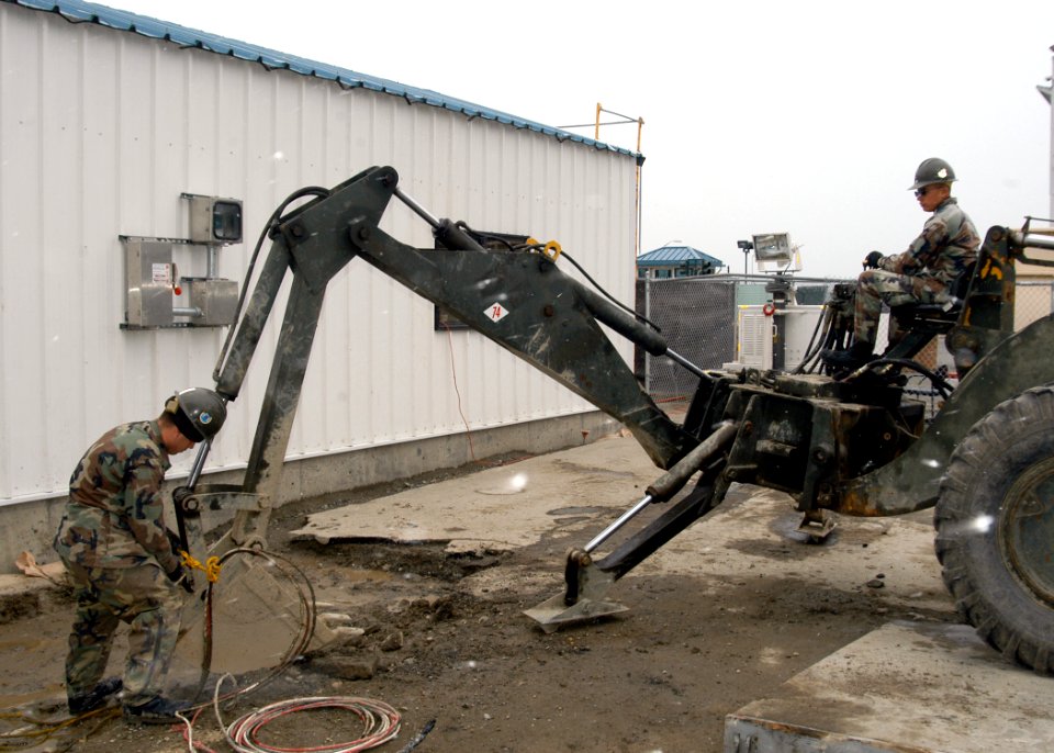 US Navy 070302-N-6247M-020 Construction Electrician Constructionman Joshua Gonzales, from San Diego, Calif., attaches old wires outside a prefabricated building while Equipment Operator Constructionman Jonathan Rust, from Tular