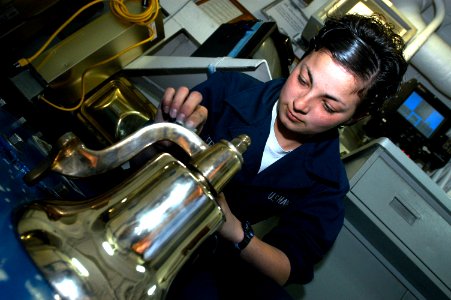 US Navy 070301-N-5484G-018 Seaman Justine Terfehr, assigned to deck department, polishes a bell to display Navy pride aboard the nuclear-powered aircraft carrier USS Nimitz (CVN 68)