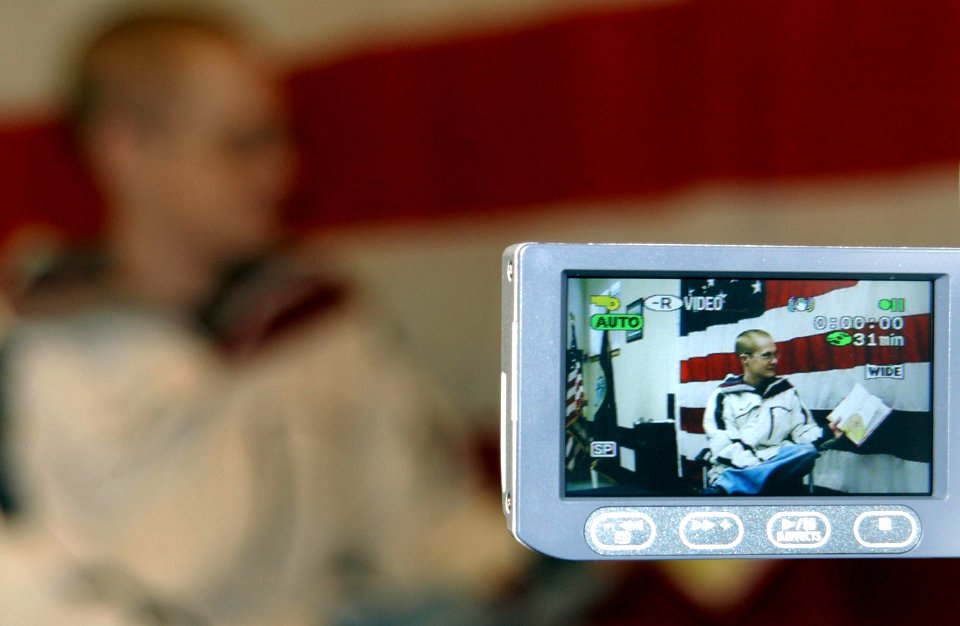 US Navy 070228-N-2143T-001 Electronics Technician 2nd Class Joshua Nyegard, assigned to USS Nevada (SSBN 733), reads a book to his children during a United Through Reading (UTR) taping