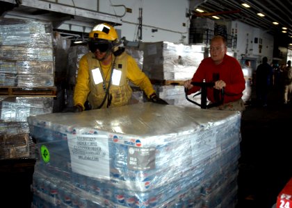 US Navy 070303-N-2636M-013 Airman Marc Silva and Chief Gunner's Mate Joseph Mclendon transfer pallets in the hangar bay aboard amphibious assault ship USS Bataan (LHD 5)