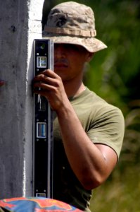 US Navy 070305-N-8154G-208 Lance Cpl. Eric Pabon, assigned to Combat Logistics Battalion (CLB) 26, 26th Marine Expeditionary Unit (MEU), levels a fence post before setting it into place