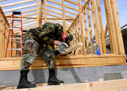 US Navy 070305-N-3857R-001 Builder 2nd Class Edward Collins uses a circular saw while constructing a storage shed to be used by the Steelworker's School at Gulfport photo