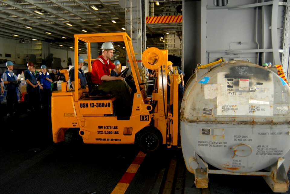 US Navy 070309-N-3038W-082 Aviation Ordnanceman Airman Deven Reed maneuvers a jet engine container in the hangar bay aboard Nimitz-class aircraft carrier USS John C. Stennis (CVN 74) during an underway replenishment