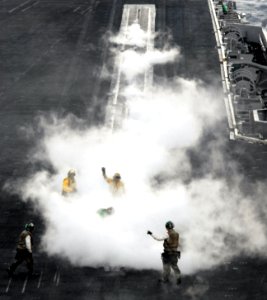 US Navy 070315-N-3659B-041 Standing in the steam of catapult one, an aircraft handler raises his hand to signal that he has control of an aircraft aboard USS Ronald Reagan (CVN 76)