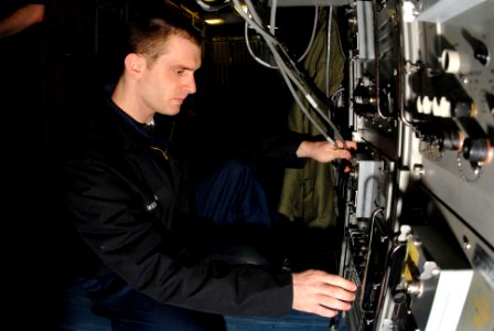 US Navy 070306-N-3038W-086 Information Systems Technician 2nd Class Dan Wiessman, assigned to combat systems department, checks satellite communications for voice networks aboard Nimitz-class aircraft carrier USS John C. Stenni photo