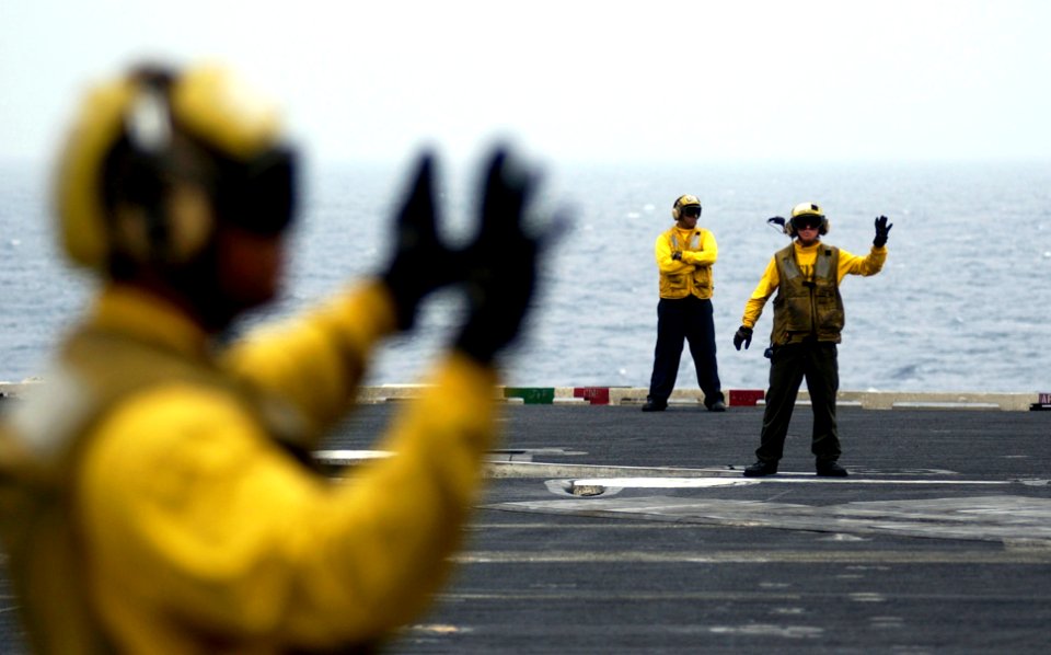 US Navy 070315-N-7130B-053 On the flight deck of USS Ronald Reagan (CVN 76), aircraft handlers work in concert with one another to safely and expeditiously move aircraft during cyclic flight operations