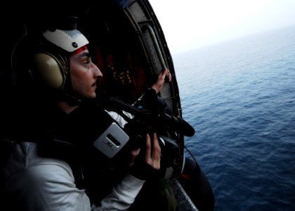 US Navy 070310-N-9928E-044 Mass Communication Specialist Seaman Matthew Hepburn takes aerial footage of a replenishment at sea photo