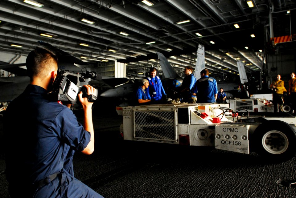 US Navy 070310-N-9928E-133 Mass Communication Specialist 3rd Class Elliot Fabrizio films sailors as they prepare to move an aircraft in the hangar bay aboard Nimitz-class aircraft carrier USS John C. Stennis (CVN 74)