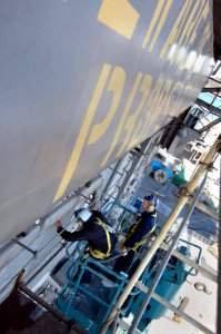 US Navy 070312-N-7883G-111 Airman Gilene Lopez from Carson, Calif., and Airman Ryan Waterbury from Llano, Texas, use a cherry picker to prepare the island of USS Kitty Hawk (CV 63) for painting