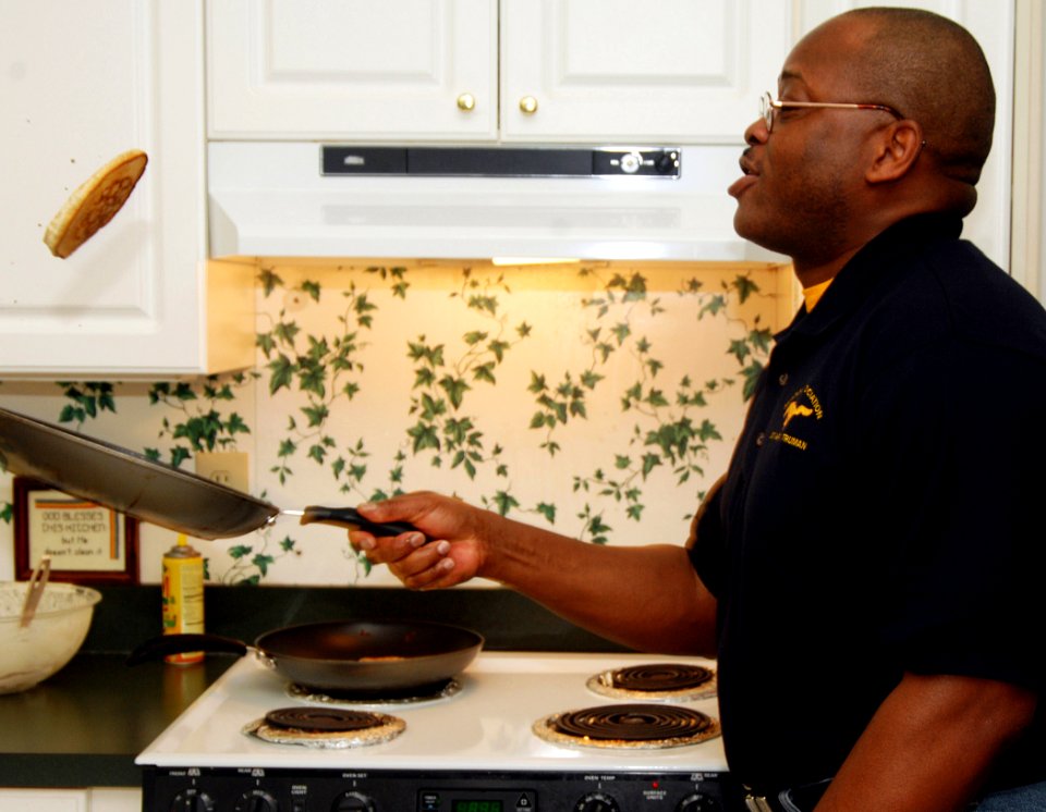 US Navy 070314-N-8923M-026 Lt. Cmdr. Eugene Mincey, USS Harry S. Truman (CVN 75) Mustang Association member, tosses a pancake in the air while preparing breakfast at the Ronald McDonald House