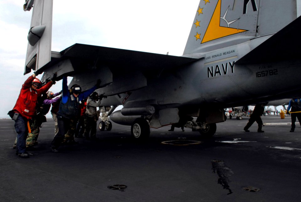 US Navy 070314-N-3659B-155 Members of Carrier Air Wing (CVW) 14 and other flight deck personnel participate in a manual push back of an F-A-18E Super Hornet, assigned to the Eagles of Strike Fighter Squadron (VFA) 115