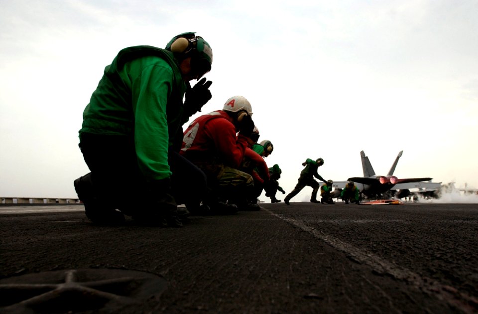 US Navy 070315-N-7130B-098 After an F-A-18E Super Hornet, assigned to the Fighting Redcocks of Strike Fighter Squadron (VFA) 22, rockets down the flight deck of USS Ronald Reagan (CVN 76), ground crews move to res