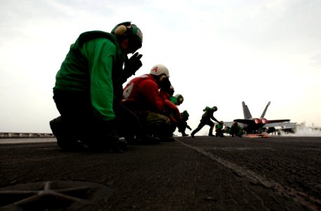 US Navy 070315-N-7130B-098 After an F-A-18E Super Hornet, assigned to the Fighting Redcocks of Strike Fighter Squadron (VFA) 22, rockets down the flight deck of USS Ronald Reagan (CVN 76), ground crews move to res