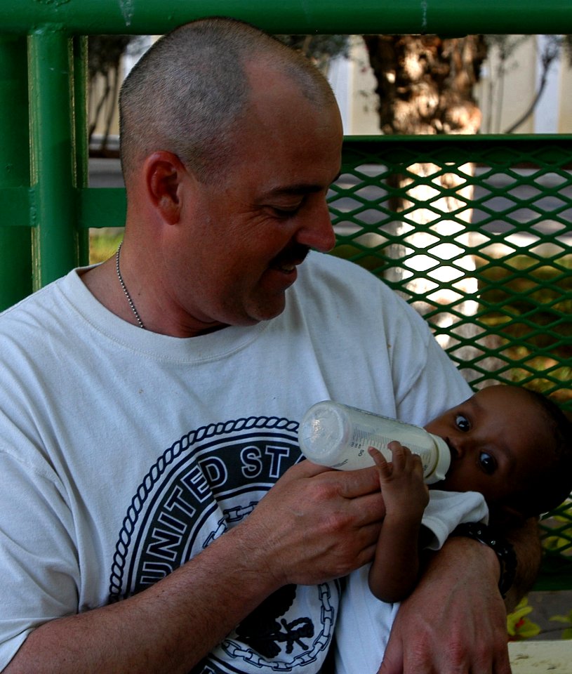US Navy 070316-N-1003P-004 Master Chief Engineman Shannon Thornton feeds a baby boy a bottle of formula while visiting a baby orphanage in Djibouti