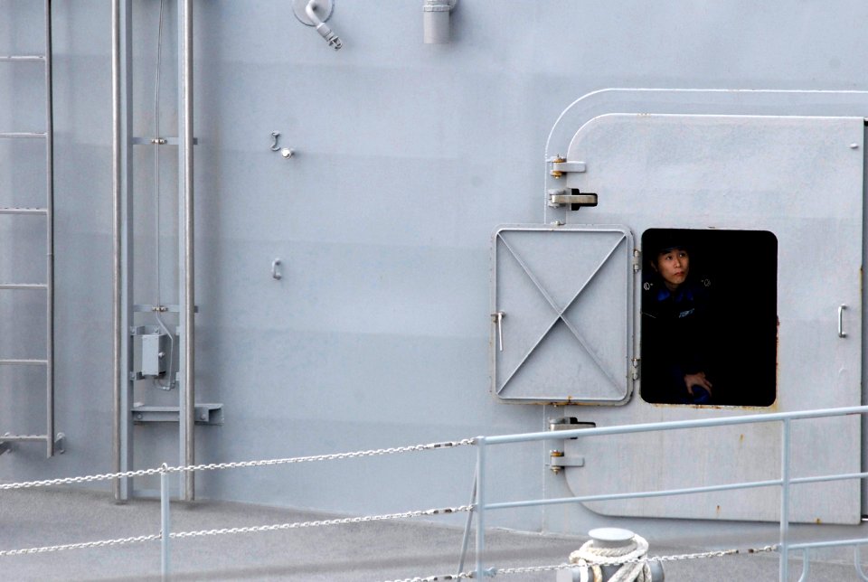 US Navy 070317-N-7730P-201 A sailor assigned to Japan Maritime Self Defense Force (JMSDF) ship JS Myoko (DDG 175) peeks out through a porthole in the superstructure to look at Nimitz-class aircraft carrier USS Ronald Reagan (CV