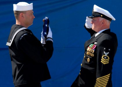 US Navy 070323-N-8102J-196 USS John F. Kennedy (CV 67) Senior Sailor of the Year, Electronics Technician 1st Class Craig T. Johnson, delivers the ensign to Command Master Chief Charles L. Dassance during the ship's decommission