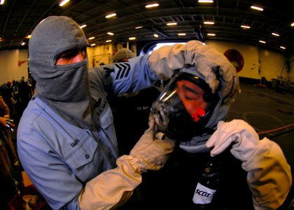 US Navy 070320-N-7981E-202 Personnel Specialist 1st Class John Smith helps Personnel Specialist 1st Class Bernardino Bardos don a Self Contained Breathing Apparatus (SCBA) used for fire fighting during a general quarters drill