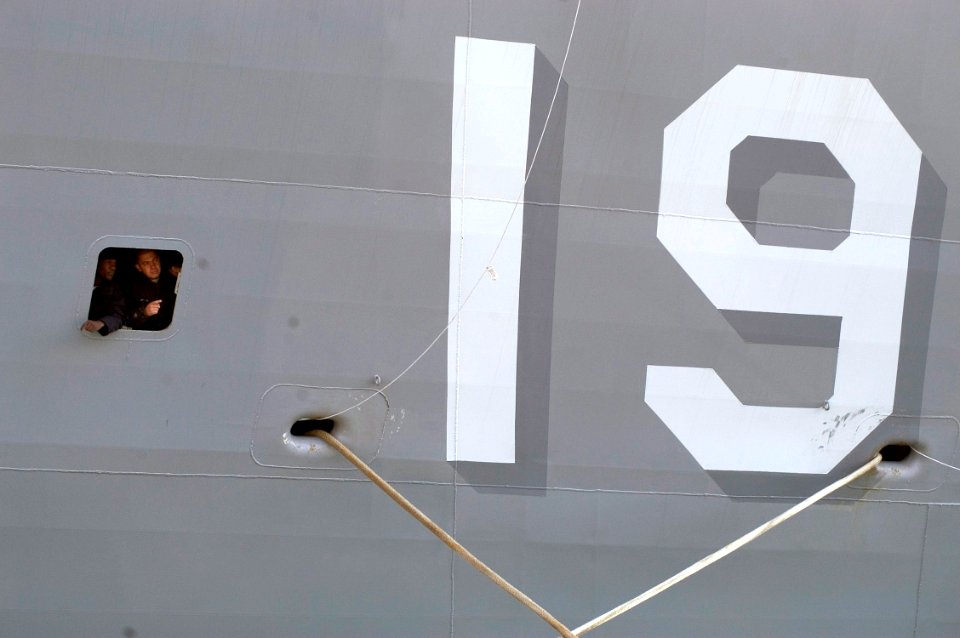 US Navy 070321-N-5253W-003 Sailors aboard amphibious command ship USS Blue Ridge (LCC 19) peer from a porthole as Blue Ridge pulls into forward deployed operating base Fleet Activities Yokosuka