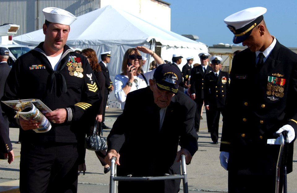 US Navy 070323-N-3285B-018 Rear Adm. Julian Lake (Ret.) is escorted to his seat by Legalman 1st Class Michael LeBlanc and Ens. Curtis Ceaser during USS John F. Kennedy (CV 67) decommissioning ceremony in Mayport