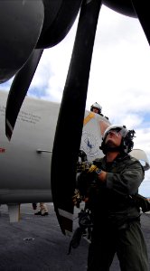 US Navy 070326-N-5345W-086 Lt. Troy Nesbitt, a naval flight officer assigned to the Seahawks of Carrier Airborne Early Warning Squadron (VAW) 126, inspects the propeller of an E-2C Hawkeye