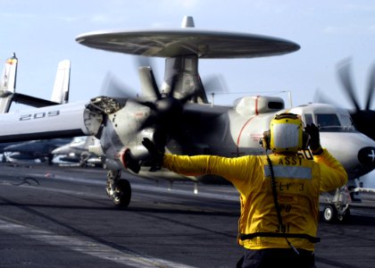 US Navy 070327-N-8446A-001 A plane director moves an E-2C Hawkeye, assigned to the Tigertails of Carrier Airborne Early Warning Squadron (VAW) 125, after landing on the flight deck of Nimitz-class aircraft carrier USS Dwight D