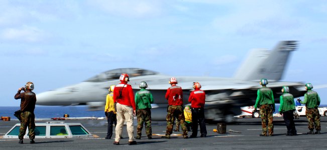 US Navy 070327-N-5345W-078 Flight deck Sailors watch from behind the safe shot line as an F-A-18F Super Hornet, assigned to the Swordsmen of Strike Fighter Squadron (VFA) 32, streaks past bow catapult number one during flight o