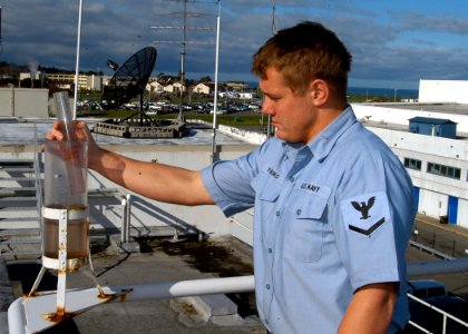 US Navy 070327-N-6247M-015 Aerographer's Mate 3rd Class Timothy Fleming checks the rain meter during an hourly weather observation, meteorological aviation observation report