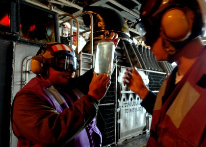 US Navy 070403-N-4954I-136 Senior Chief Aviation Boatswain's Mate (Fuels) Jerome Ba Maung, left, and Aviation Boatswain's Mate (Fuels) 3rd Class Cody Wright examine a JP-5 fuel sample taken from a Landing Craft Air Cushion (LCA