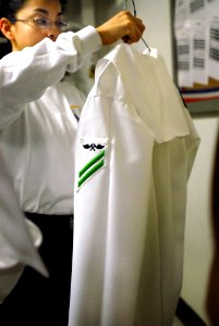 US Navy 070406-N-4133B-067 Ship's Serviceman 2nd Class Marcela Kan'ae, from Fabens, Texas, inspects one of her shipmate's dress white uniform prior to manning-the-rails